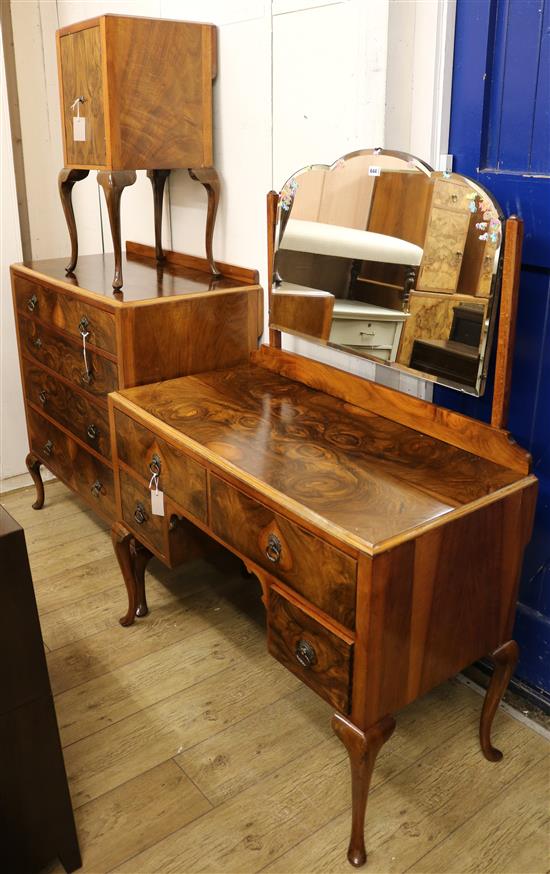 A matched walnut suite of bedroom furniture, comprising a cupboard, a dressing table and a chest of drawers